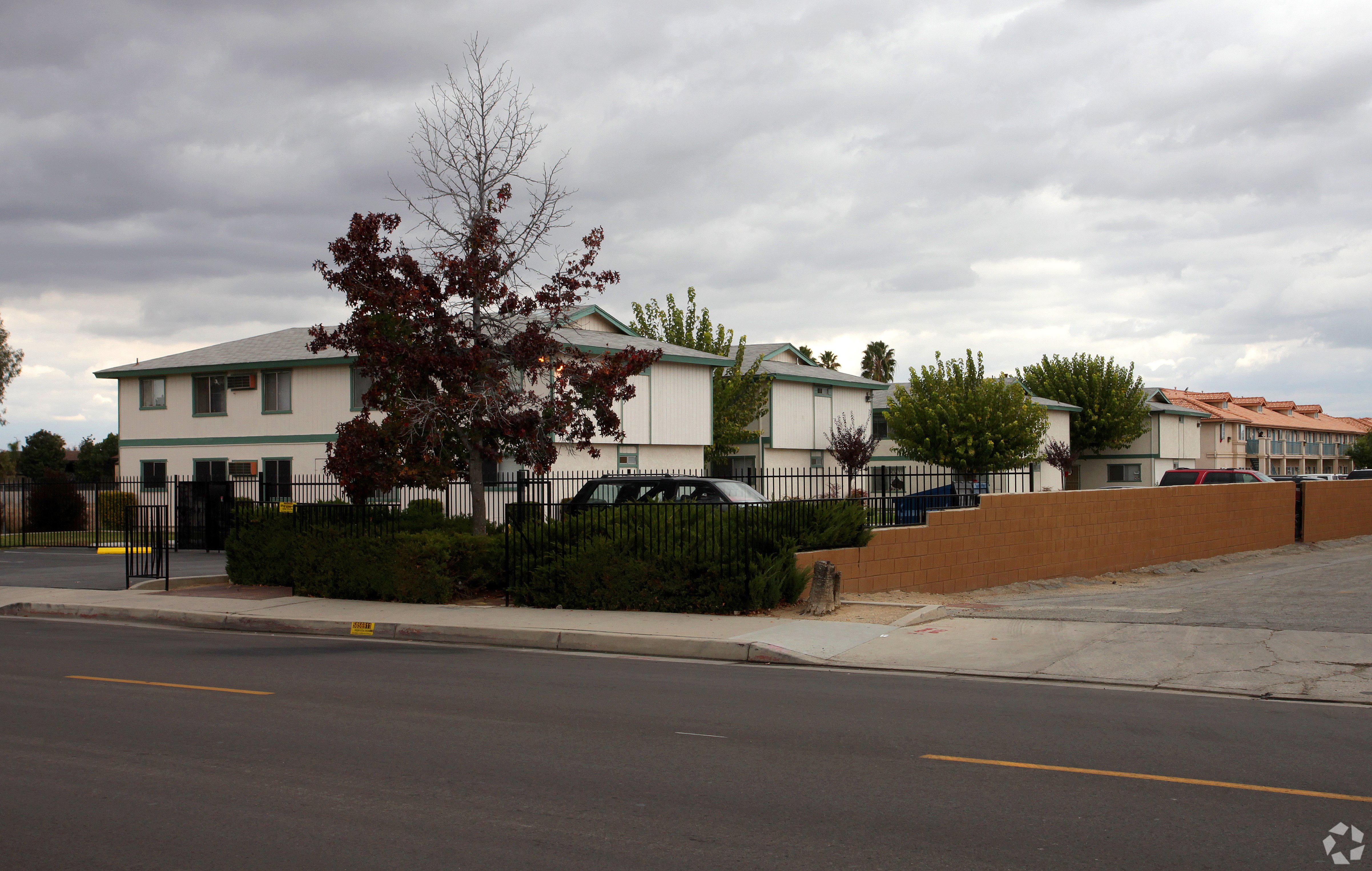 A white building with a green roof is surrounded by a black fence.